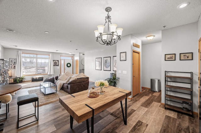 dining space with an inviting chandelier, a textured ceiling, wood finished floors, and recessed lighting