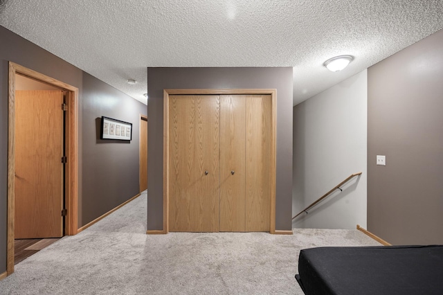 interior space featuring carpet, baseboards, a textured ceiling, and an upstairs landing