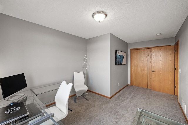 unfurnished office featuring a textured ceiling, carpet, and baseboards