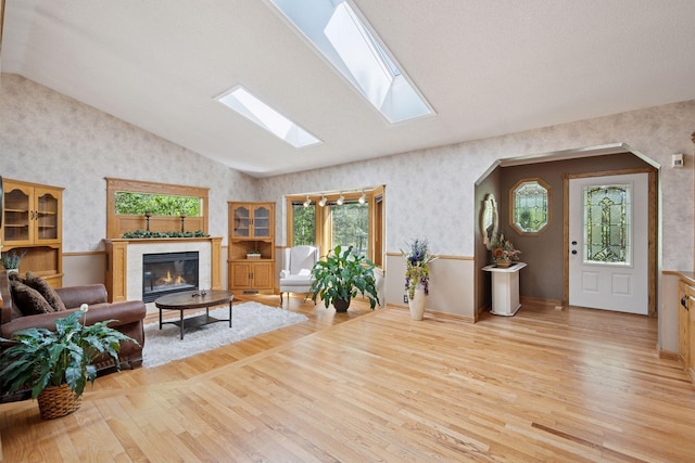 3415 197th Ave NW, Oak Grove, MN 55303 - living area featuring vaulted ceiling, wallpapered walls, wood finished floors, a glass covered fireplace, and a skylight