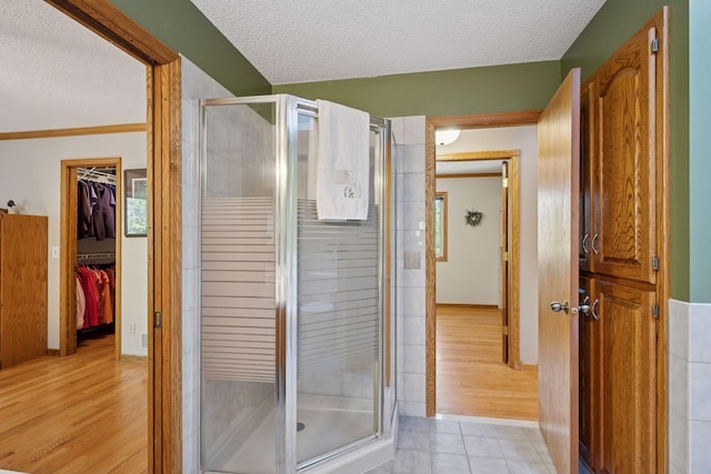 3415 197th Ave NW, Oak Grove, MN 55303 - bathroom featuring a textured ceiling, a shower stall, a spacious closet, and tile patterned flooring