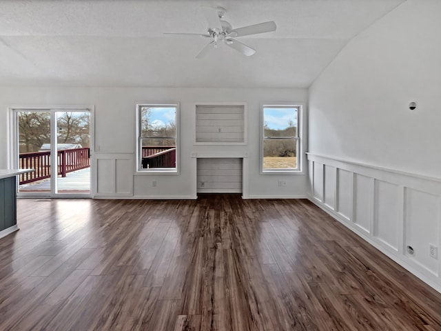 unfurnished living room with vaulted ceiling, dark wood finished floors, a ceiling fan, and a healthy amount of sunlight