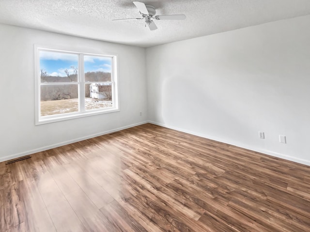 unfurnished room featuring a ceiling fan, visible vents, a textured ceiling, and wood finished floors