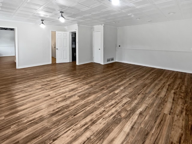 empty room with an ornate ceiling, visible vents, baseboards, and wood finished floors