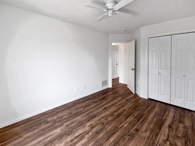 unfurnished bedroom with ceiling fan, visible vents, baseboards, a closet, and dark wood finished floors