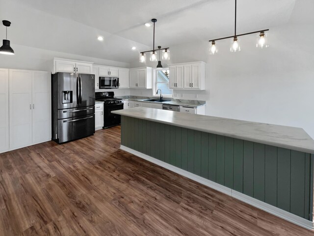 kitchen with lofted ceiling, a sink, white cabinets, appliances with stainless steel finishes, and dark wood finished floors