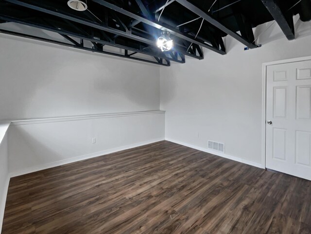 basement featuring dark wood-style flooring, visible vents, and baseboards