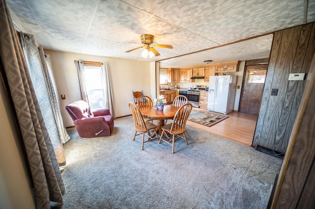 dining area with light carpet, a healthy amount of sunlight, baseboards, and a ceiling fan