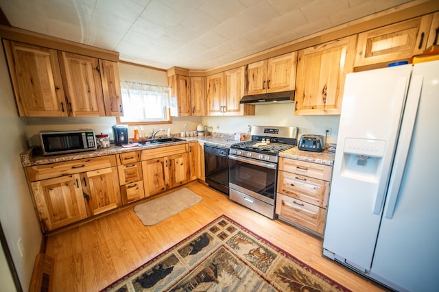 kitchen with light wood-type flooring, under cabinet range hood, visible vents, appliances with stainless steel finishes, and a sink