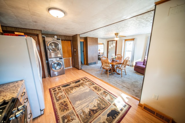 interior space with freestanding refrigerator, ceiling fan, visible vents, gas stove, and stacked washer / drying machine