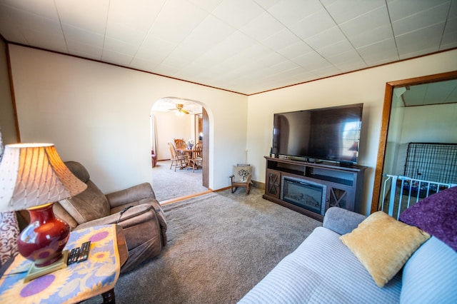 carpeted living room featuring arched walkways and a ceiling fan