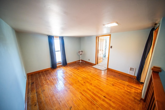 spare room featuring light wood finished floors, baseboards, and visible vents