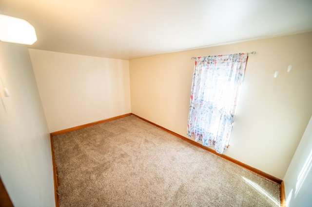 unfurnished room with light carpet and baseboards
