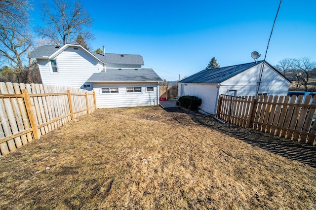 back of property with a fenced backyard and a lawn
