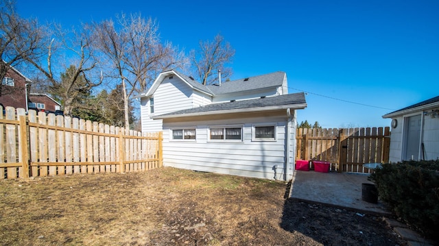 back of house featuring fence and a shingled roof