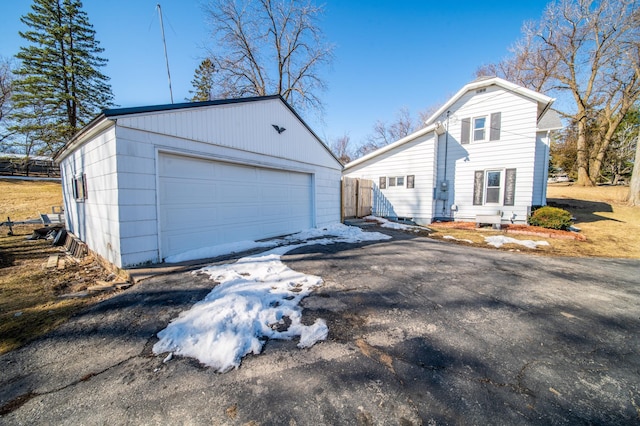 view of front facade with an outbuilding, a detached garage, and fence
