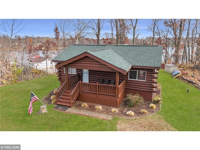 log home with stairs, a shingled roof, a front yard, and log siding