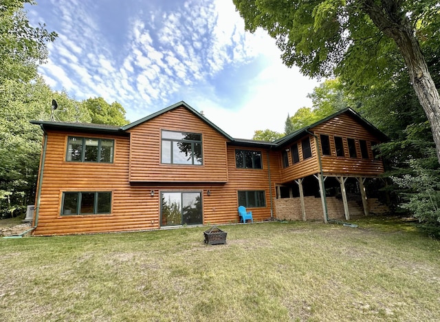 rear view of property featuring faux log siding and a yard