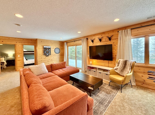 carpeted living room featuring a textured ceiling, wood walls, visible vents, and recessed lighting