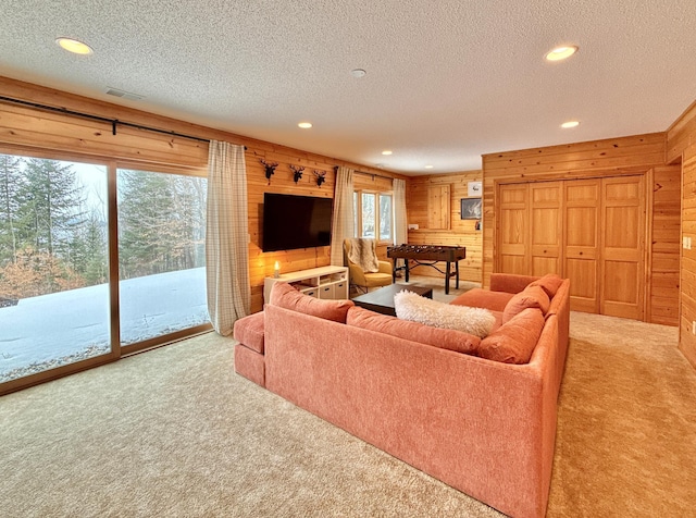 carpeted living room featuring recessed lighting, a healthy amount of sunlight, wooden walls, and a textured ceiling