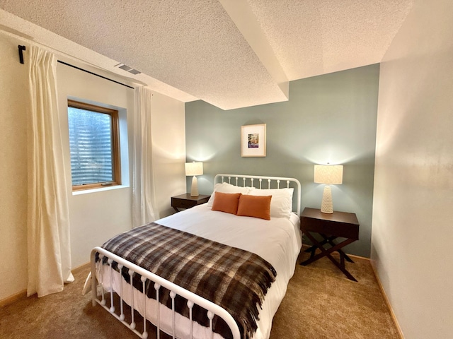 carpeted bedroom featuring baseboards, visible vents, and a textured ceiling