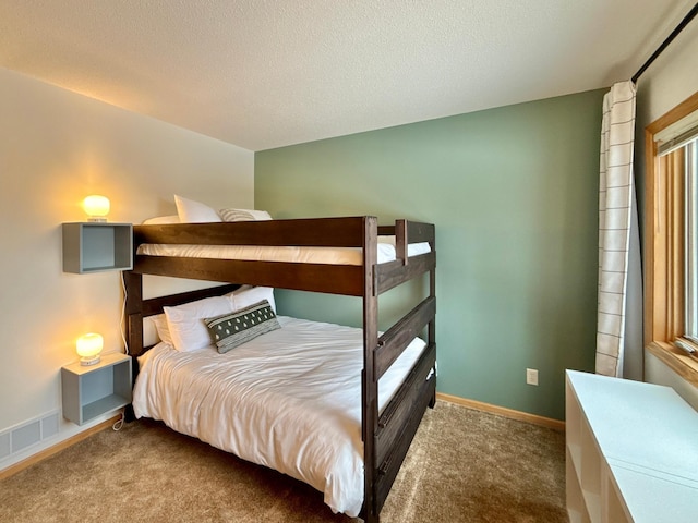 bedroom featuring a textured ceiling, carpet, visible vents, and baseboards