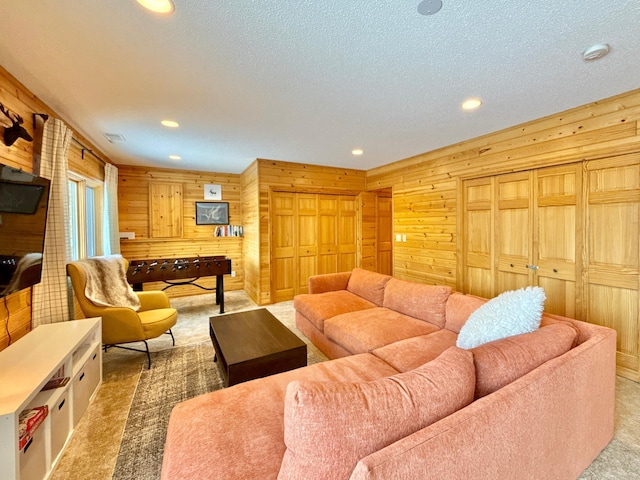 carpeted living area with a textured ceiling, recessed lighting, and wooden walls