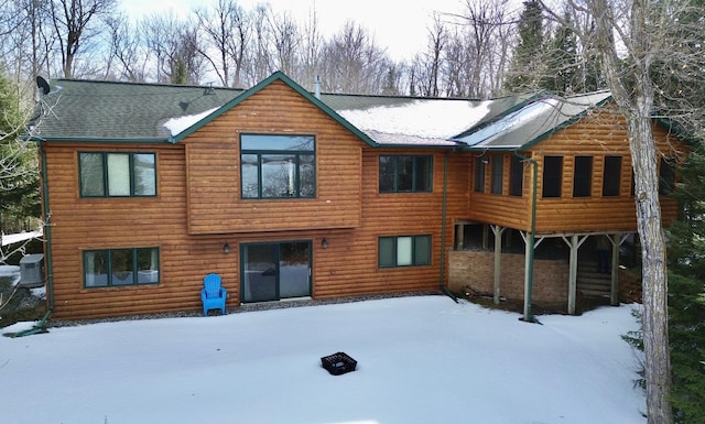 snow covered back of property featuring log veneer siding