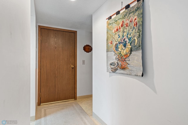 hallway featuring a textured ceiling and baseboards