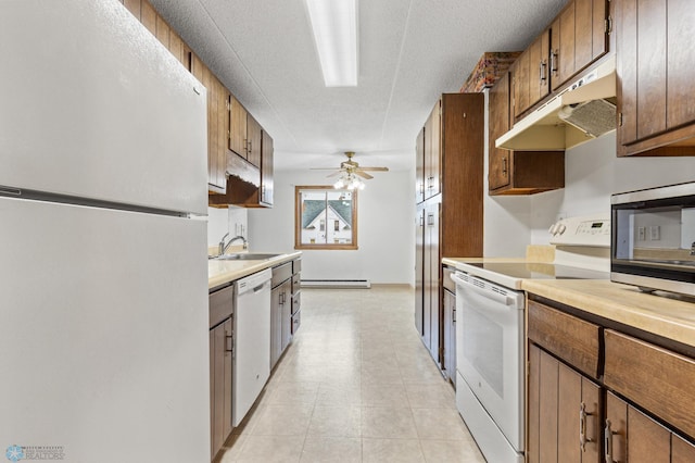 kitchen with white appliances, brown cabinets, light countertops, under cabinet range hood, and a sink