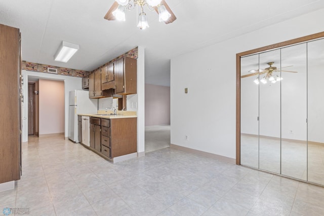 kitchen featuring visible vents, ceiling fan, brown cabinets, light countertops, and a sink