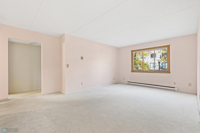 spare room featuring a baseboard heating unit, light carpet, and baseboards