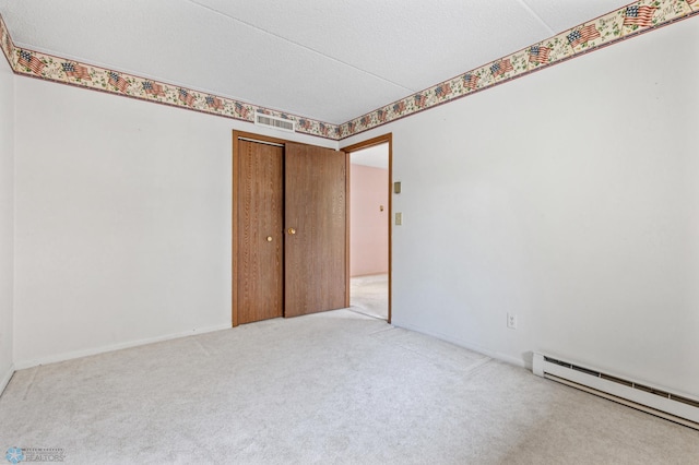 unfurnished room with visible vents, a baseboard heating unit, carpet flooring, a textured ceiling, and baseboards