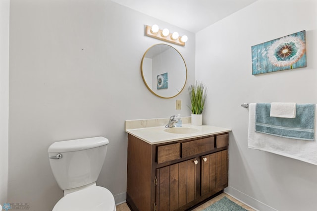 bathroom with toilet, vanity, and baseboards