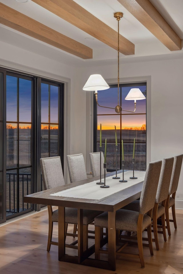 dining space with beamed ceiling and wood finished floors