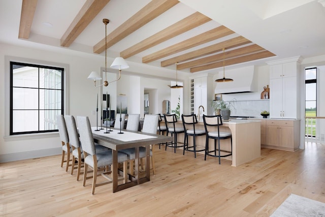 dining area featuring light wood-type flooring, baseboards, and beam ceiling