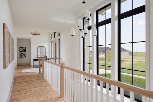 hall with baseboards, an upstairs landing, and wood finished floors