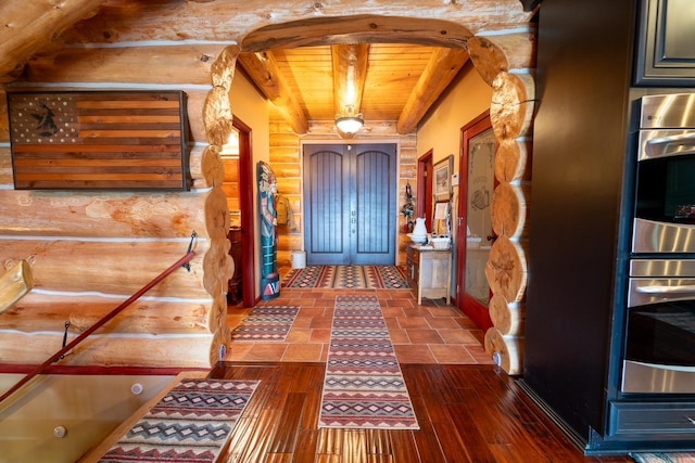 entryway featuring rustic walls, arched walkways, wood ceiling, dark wood-type flooring, and beamed ceiling