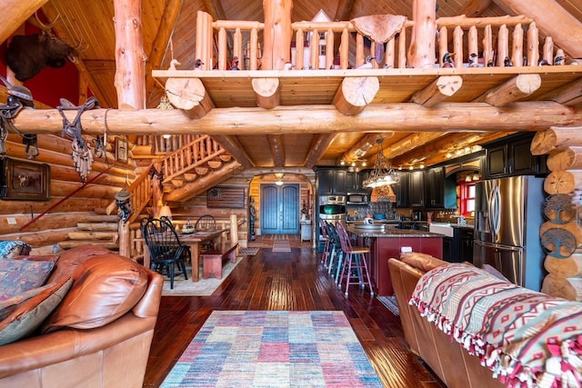 living area with dark wood-style flooring, wooden ceiling, beamed ceiling, and log walls