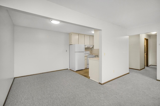 kitchen featuring under cabinet range hood, light carpet, white appliances, light countertops, and cream cabinetry