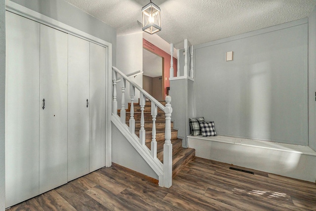 stairs featuring a textured ceiling and wood finished floors