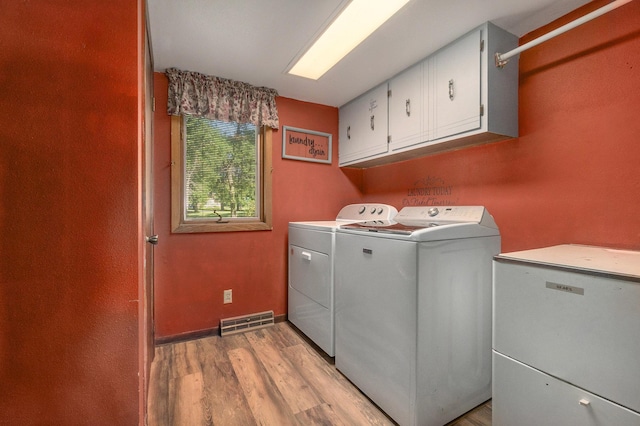 laundry area featuring cabinet space, baseboards, visible vents, washer and clothes dryer, and light wood-style floors