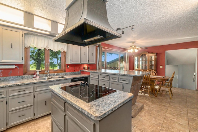 kitchen featuring a center island, island exhaust hood, black electric cooktop, a textured ceiling, and a sink