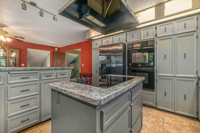 kitchen with a kitchen island, gray cabinets, a textured ceiling, black appliances, and exhaust hood