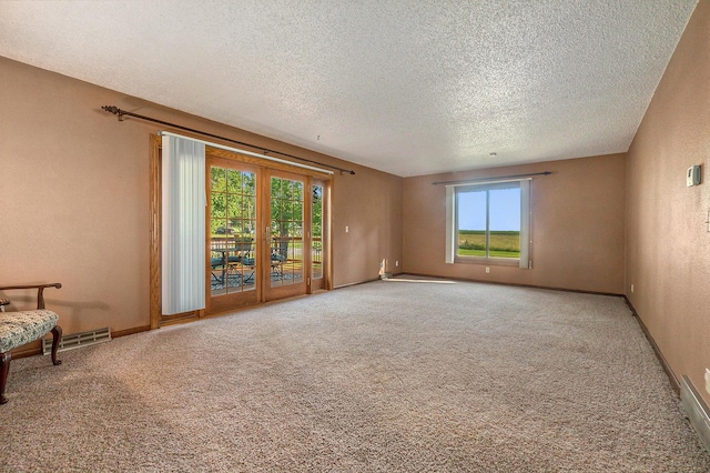 interior space with carpet, visible vents, baseboards, and a textured ceiling