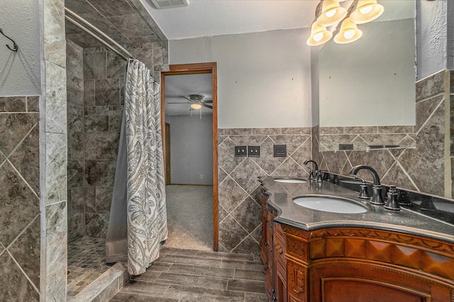 full bathroom featuring a notable chandelier, tile walls, a stall shower, wainscoting, and vanity