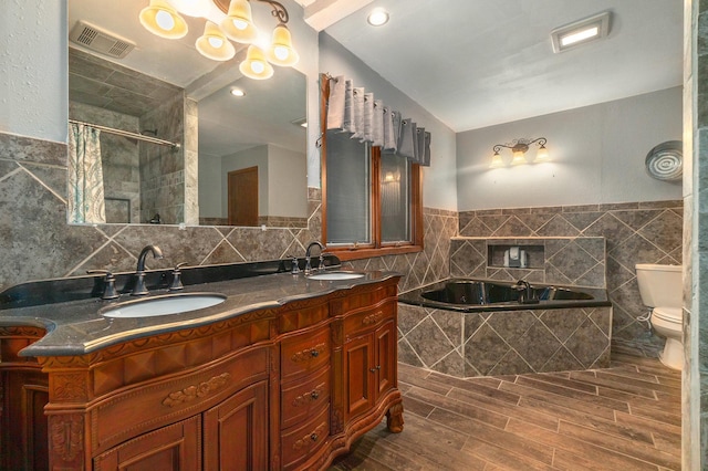 bathroom featuring a garden tub, a sink, visible vents, and tile walls