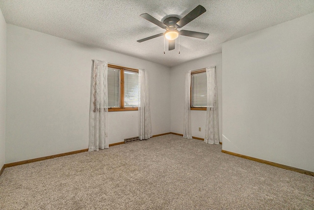 empty room with a textured ceiling, carpet floors, and baseboards