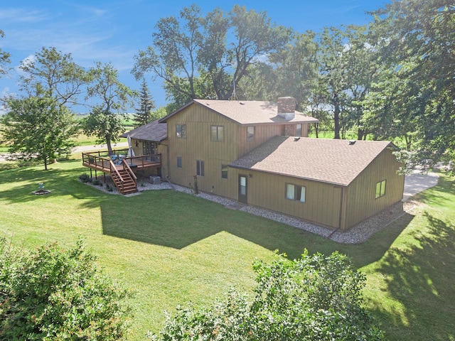 exterior space featuring a shingled roof, a wooden deck, a chimney, stairway, and a yard