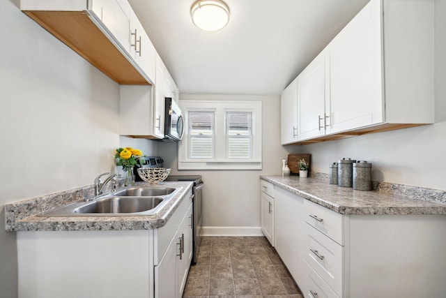 kitchen with stainless steel appliances, light countertops, a sink, and baseboards